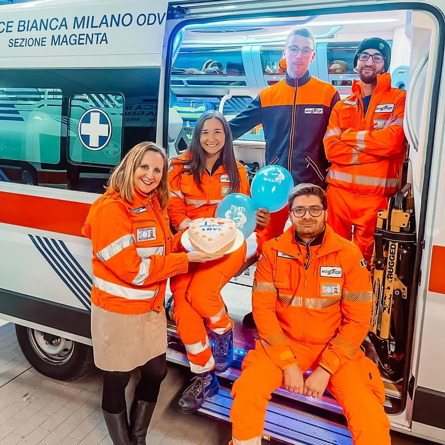 Un equipaggio di Croce Bianca Magenta festeggia sul portellone dell'ambulanza